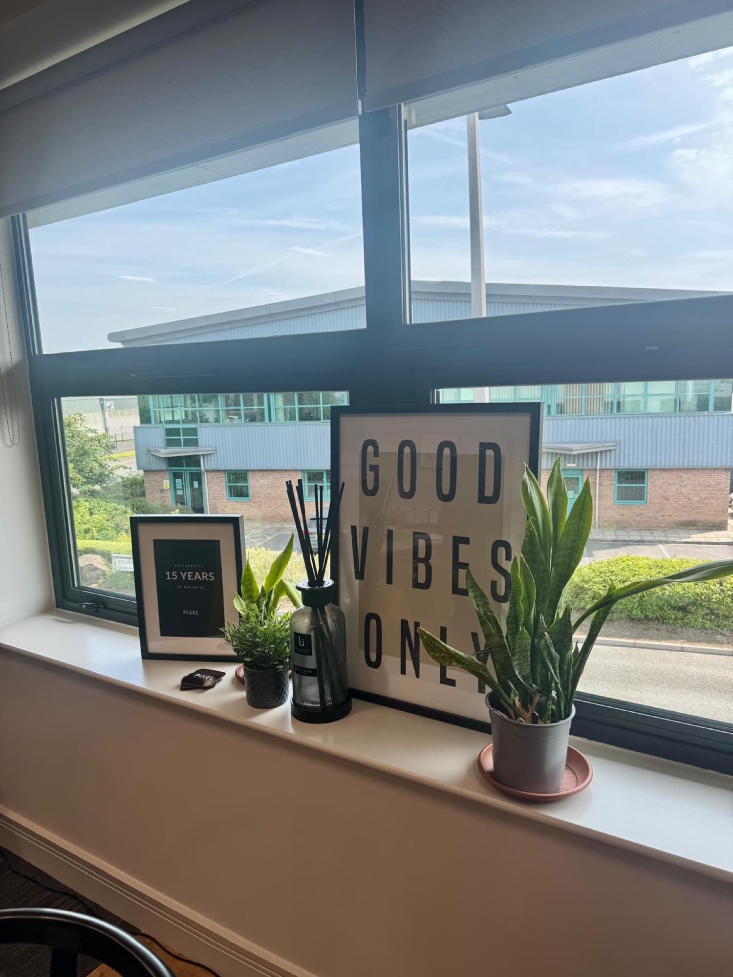 Windowsill in the Pixel office with plants and a Good Vibes Only print
